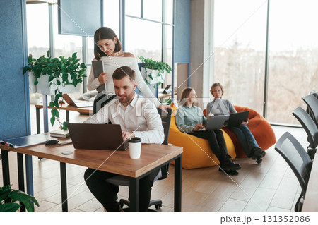 Career growth. Using laptops. People are working in the office with bean bags chairs in it Career growth. Using laptops. People are working in the office with bean bags chairs in it 131352086
