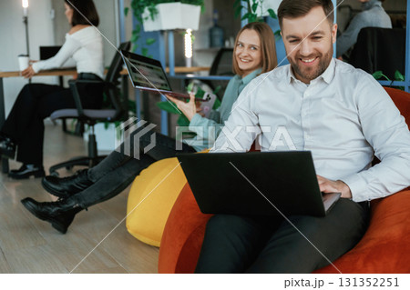 Soft bean bags. Sitting in comfort with laptop. People are working in the office Soft bean bags. Sitting in comfort with laptop. People are working in the office 131352251