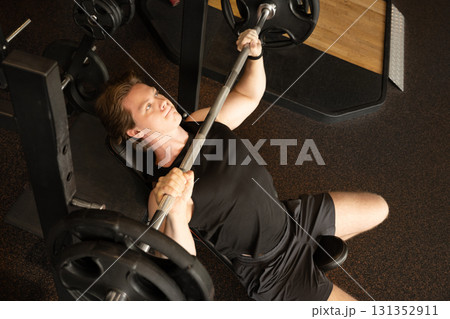 Sporty caucasian man or bodybuilder exercising bench press at fitness center. Male athlete lifting weights. 131352911