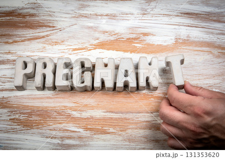 Pregnant Word Formed with Concrete Letters and Human Hand on Rustic Wooden Background 131353620
