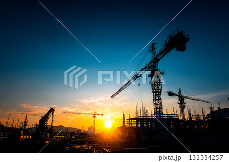 オレンジ色の空を背景にした建築中のビルとタワークレーンのシルエット 131354257