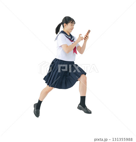 スマホを見ながらジャンプするセーラー服を着た女子学生　手作業で精密に切り抜いた背景透過全身写真PNG 131355988