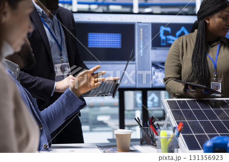 Photovoltaics factory engineer meeting with investors using laptop to highlight key elements of solar panel design. Manager using notebook to do presentation of industrial energy solutions, close up 131356923