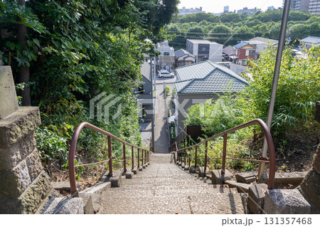 神社から下る長く細い石段と遠景の街並み 131357468