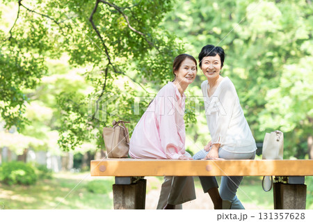 新緑の公園で談笑するシニア女性 131357628