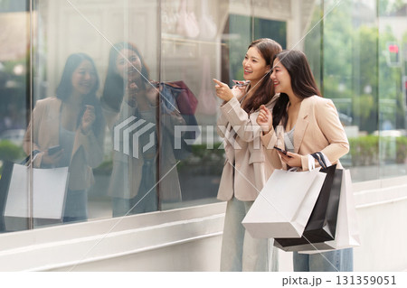 Black Friday Shopping. Two women admiring window displays while holding shopping bags. 131359051