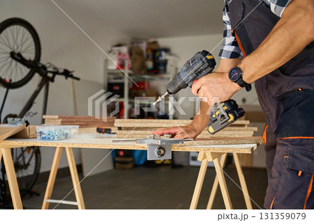 Carpenter drilling wooden panel using jig tool for precise holes Carpenter drilling wooden panel using jig tool for precise holes 131359079