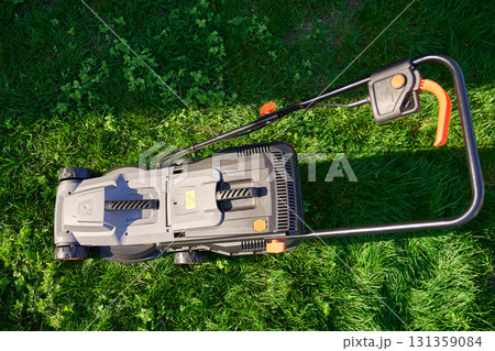 Electric lawnmower on green grass in backyard 131359084