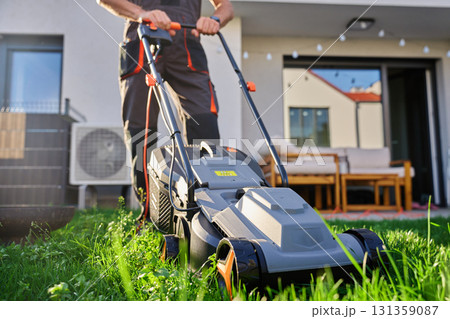 Man mowing lawn with electric mower in backyard 131359087