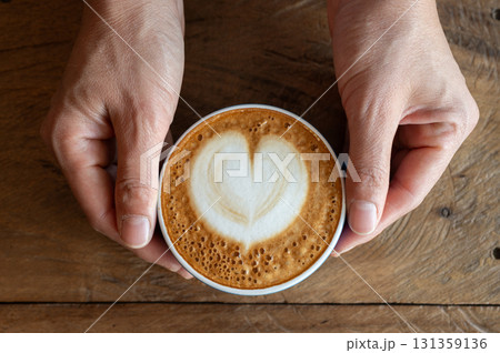 Woman hands holding a cup of hot Cappuccino coffee before drinking. The taste of cappuccinos can be described as creamy, smooth, and balanced. Woman hands holding a cup of hot Cappuccino coffee before drinking. The taste of cappuccinos can be described as creamy, smooth, and balanced. 131359136