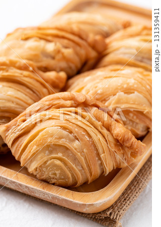Curry puff stuffed with chicken or sweet potatoes on wooden plate, Thai snack food style Curry puff stuffed with chicken or sweet potatoes on wooden plate, Thai snack food style 131359411