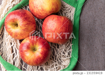 Top view of red apple fruit (Envy apple) in mesh bag on brown fabric background Top view of red apple fruit (Envy apple) in mesh bag on brown fabric background 131359419