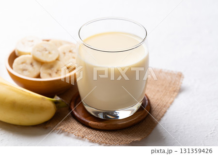 Banana milk in glass with sliced banana and fruit on white background 131359426
