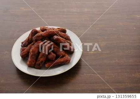 テーブル背景の皿に盛った黒糖かりんとう(黒かりんとう) 131359655