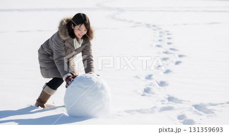 冬の雪景色で雪だるま作りを楽しむ女性 冬の雪景色で雪だるま作りを楽しむ女性 131359693