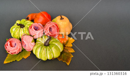 Autumn composition with pumpkins, autumn leaves and pink flowers on a gray background with space for text Autumn composition with pumpkins, autumn leaves and pink flowers on a gray background with space for text 131360316
