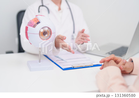 Elderly Patient consulting Doctor to Eye disease, Senior Medical Diagnosis. Anatomy Eye model for Cataract, Glaucoma, Age Related Macular Degeneration, Diabetic Retinopathy, Vitreous, health concept 131360580