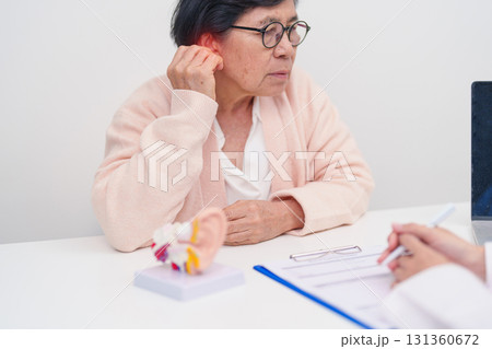 Elderly Patient consulting Doctor to Ear disease. Senior Health Medical Diagnosis. Anatomy Ear model for Atresia, Otitis Media, Pertorated Eardrum, Meniere syndrome, otolaryngologist, Hearing Loss 131360672