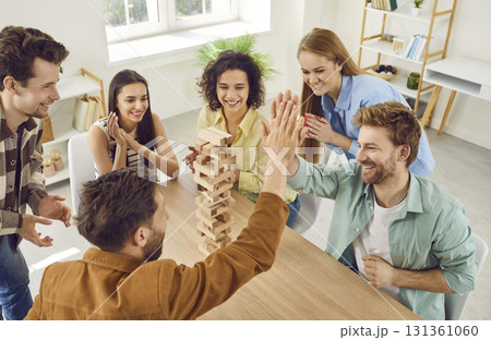 Group of a happy friends playing together with wooden building blocks at home. 131361060