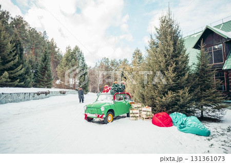 green retro car decorated with Christmas gifts and fir tree on roof covered with snow, festive winter holiday celebration and seasonal decoration outdoors green retro car decorated with Christmas gifts and fir tree on roof covered with snow, festive winter holiday celebration and seasonal decoration outdoors 131361073