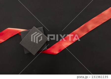 Black Friday sale concept with a black gift box and a red ribbon on a dark background. Ideal for holiday promotions and shopping events. 131361135