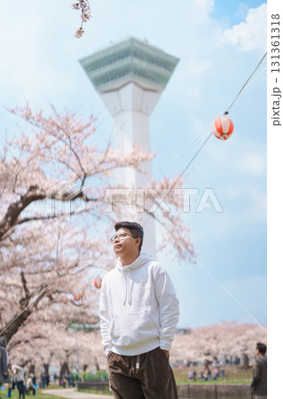 man tourist sightseeing Goryokaku Tower park with Sakura Cherry Blossom in Spring, happy traveler travel in Hakodate city, Hokkaido, Japan. famous Landmark, Japan Travel and Vacation destination 131361318