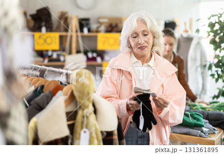 Elderly woman choosing gloves in clothing store Elderly woman choosing gloves in clothing store 131361895
