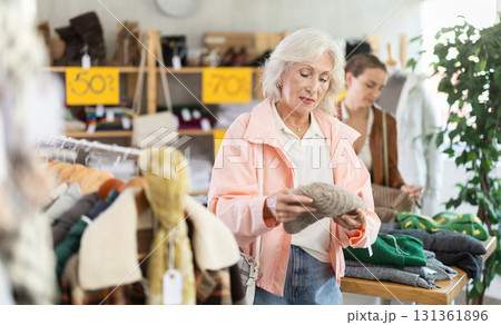 Senior woman customer examine and choose hat. Other buyer in background, crowded shop 131361896