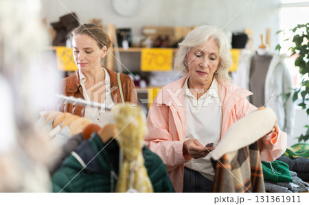 Mature woman customer examine and choose plaid jacket in store 131361911