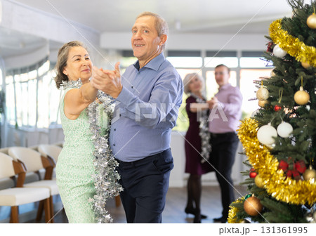 In studio decorated for New Year, elderly man and woman perky dance pair discofox. 131361995