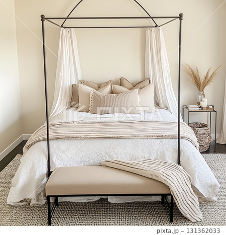 Bed with a canopy and pillows, and a bench in front of it 131362033