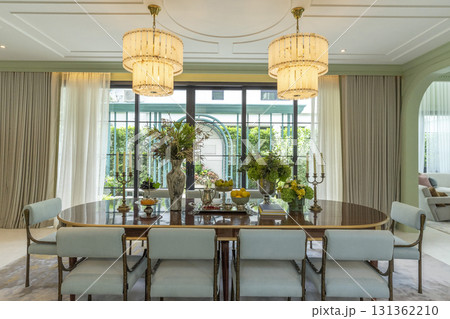 Beautiful luxurious traditional style modern dining room with bouquets of flowers on the table. Elegance dinning table with luxurious pendant. 131362210
