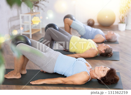 Group of elderly woman doing pilates with soft ball in studio Group of elderly woman doing pilates with soft ball in studio 131362259