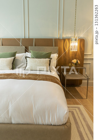 Luxury large modern bedroom in white and brown colors. On the sides are two bedside tables with lamps.  131362263