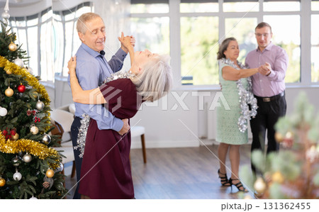 Positive senior man dancing playful Latin dance bachata with female partner during celebration Christmas and New Year in choreography studio. Active lifestyle of older generation 131362455