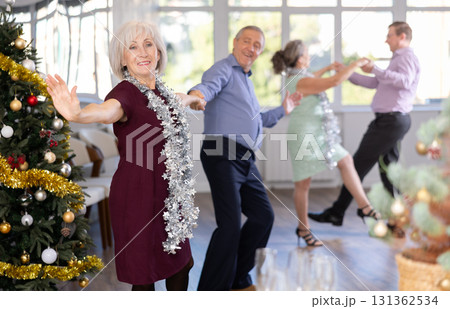 Smiling adult lady in elegant clothes dancing in couple latin dance, energetic and fast jive in dance salon during celebration Christmas and New Year Smiling adult lady in elegant clothes dancing in couple latin dance, energetic and fast jive in dance salon during celebration Christmas and New Year 131362534
