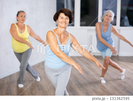 Happy mature woman practicing dance positions during workout session Happy mature woman practicing dance positions during workout session 131362595