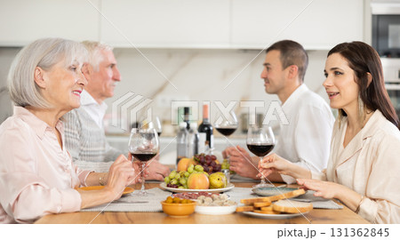 Senior parents and young couple sitting at table drinking wine and having conversation 131362845