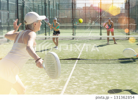 Old woman playing Padel Tennis in pairs in tennis court 131362854