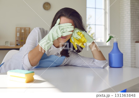 Tired woman housewife with cleaning tools standing in kitchen and cover her face with hands. 131363848