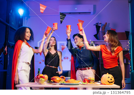 Joyful office Halloween party with coworkers in costumes, celebrating with drinks and laughter, fostering teamwork Joyful office Halloween party with coworkers in costumes, celebrating with drinks and laughter, fostering teamwork 131364795