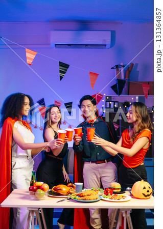 Joyful office Halloween party with coworkers in costumes, celebrating with drinks and laughter, fostering teamwork Joyful office Halloween party with coworkers in costumes, celebrating with drinks and laughter, fostering teamwork 131364857