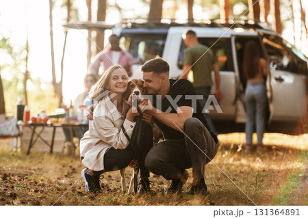 Beautiful couple is sitting with their dog. Group of friends are having fun together in the forest Beautiful couple is sitting with their dog. Group of friends are having fun together in the forest 131364891