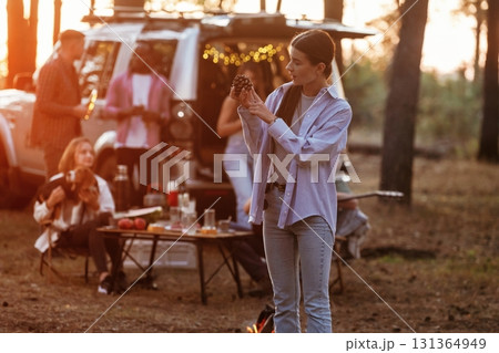 Front view of young woman that is standing against people. Group of friends are having fun together in the forest Front view of young woman that is standing against people. Group of friends are having fun together in the forest 131364949