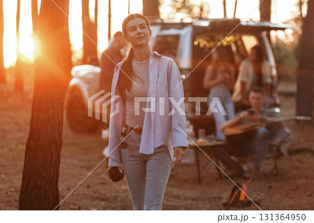Young woman is standing and posing. Group of friends are having fun together in the forest Young woman is standing and posing. Group of friends are having fun together in the forest 131364950