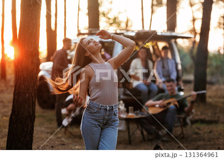 Pretty woman is standing and enjoying nature. Group of friends are having fun together in the forest 131364961