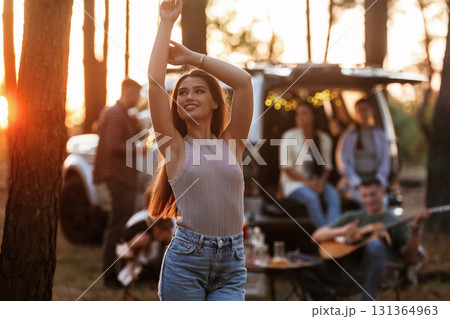 Pretty woman is standing and enjoying nature. Group of friends are having fun together in the forest Pretty woman is standing and enjoying nature. Group of friends are having fun together in the forest 131364963