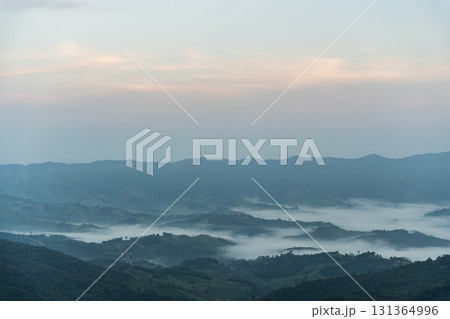 Serene Mountain Landscape at Dawn with Mist Rolling Over the Valleys and Soft Hues in the Sky, Evoking Tranquility and Natural Beauty in Italy 131364996