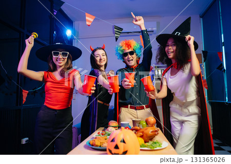 Joyful office Halloween party with coworkers in costumes, celebrating with drinks and laughter, fostering teamwork Joyful office Halloween party with coworkers in costumes, celebrating with drinks and laughter, fostering teamwork 131365026