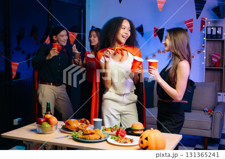 Joyful friends in vibrant Halloween costumes share drinks and laughter at a festive indoor party. 131365241